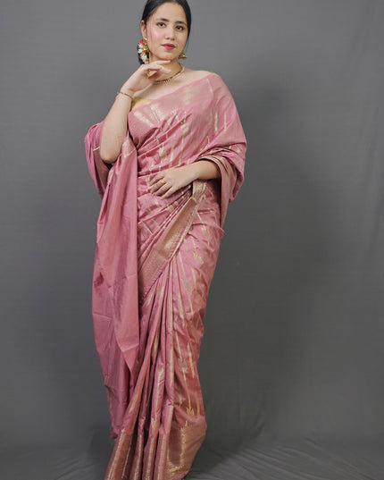 Woman wearing a pink saree against a gray background