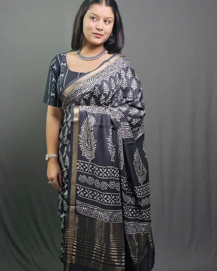 Woman wearing a black and white patterned saree against a gray background