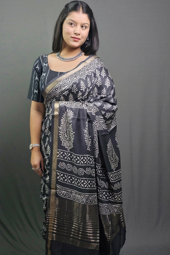 Woman wearing a black and white patterned saree against a gray background