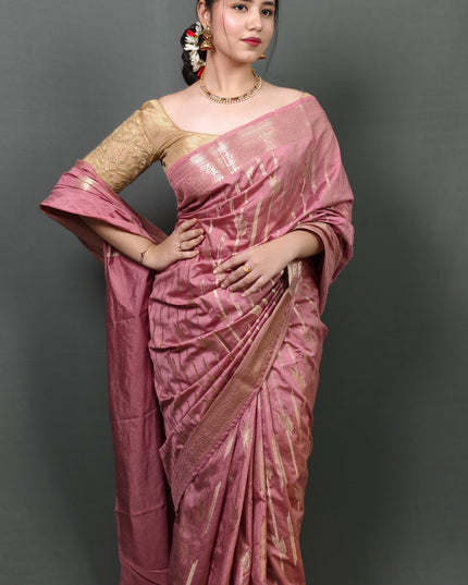 Woman wearing a pink saree with a gold blouse against a gray background
