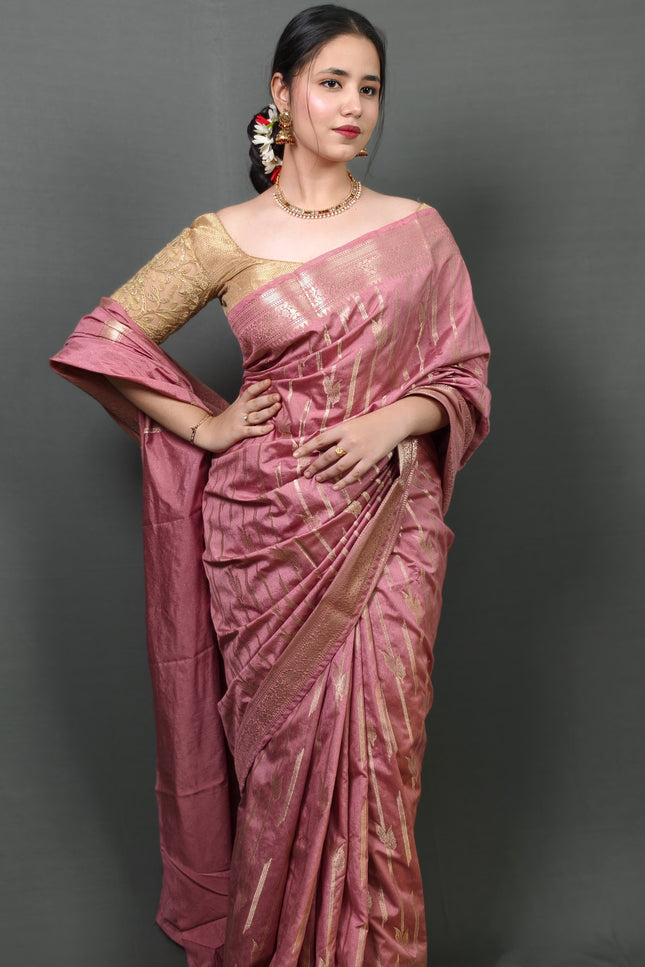 Woman wearing a pink saree with a gold blouse against a gray background