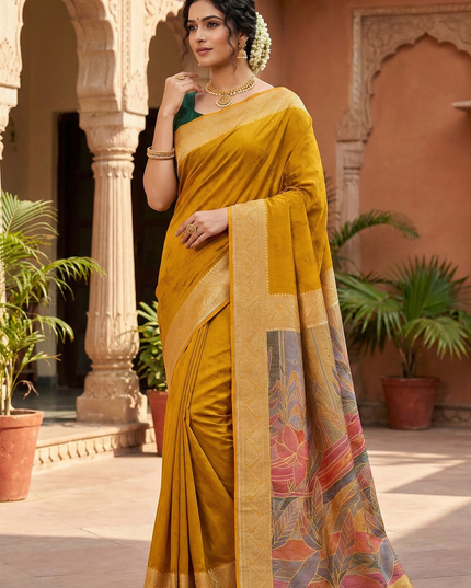 Woman in a yellow saree with a colorful border standing in an outdoor setting.